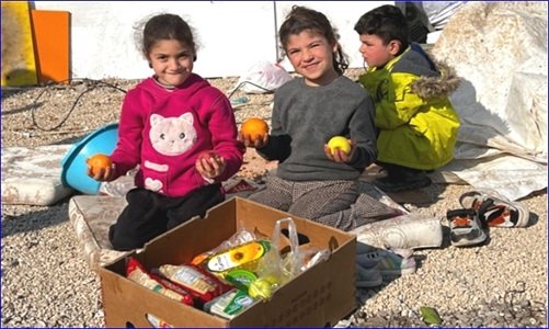 Syrische Flüchtlingsmädchen vor einer Kiste mit Hilfsgütern